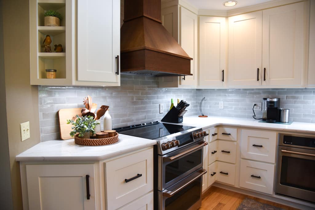 White painted custom cabinets with wood stained range hood