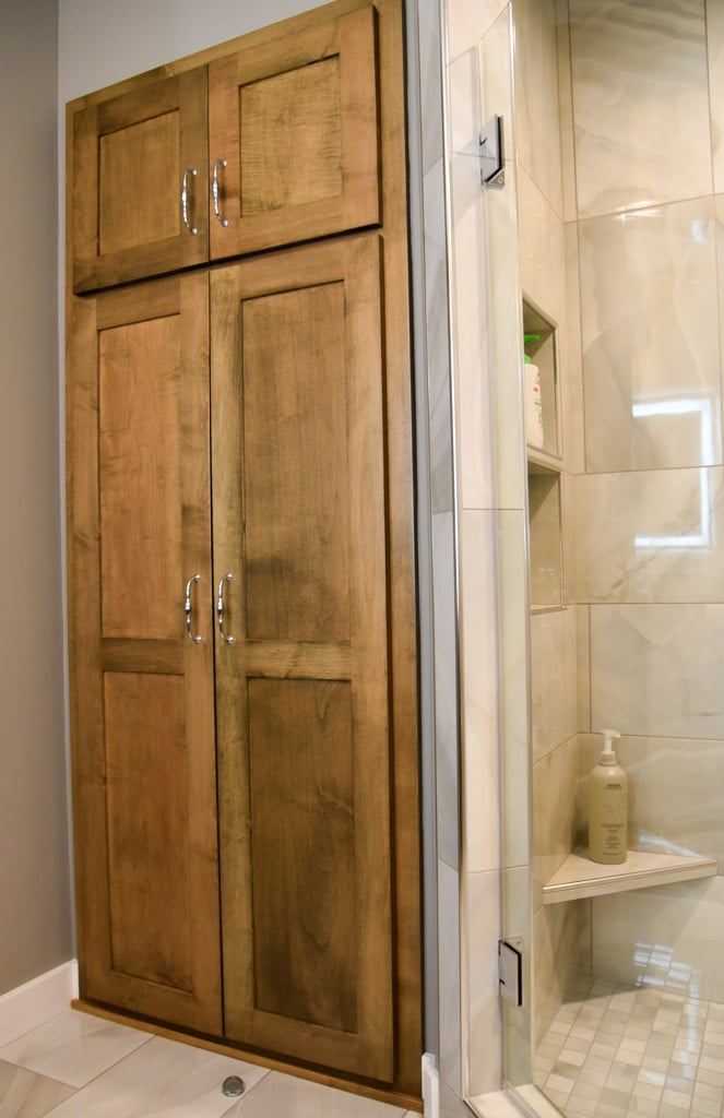 Bathroom cabinet next to shower stall stained wood